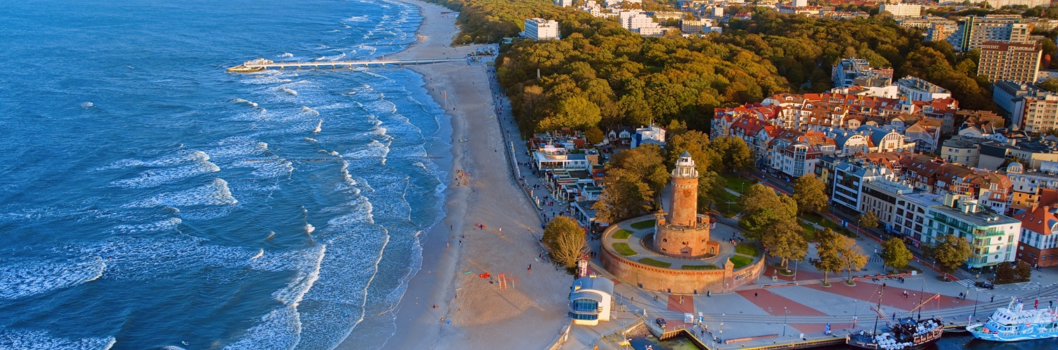 This aerial shot focuses on Kołobrzeg's iconic lighthouse and the thriving harbor beneath it. The coastal charm, combined with the maritime atmosphere of this Polish gem, is beautifully showcased.