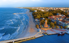 This aerial shot focuses on Kołobrzeg's iconic lighthouse and the thriving harbor beneath it. The coastal charm, combined with the maritime atmosphere of this Polish gem, is beautifully showcased.
