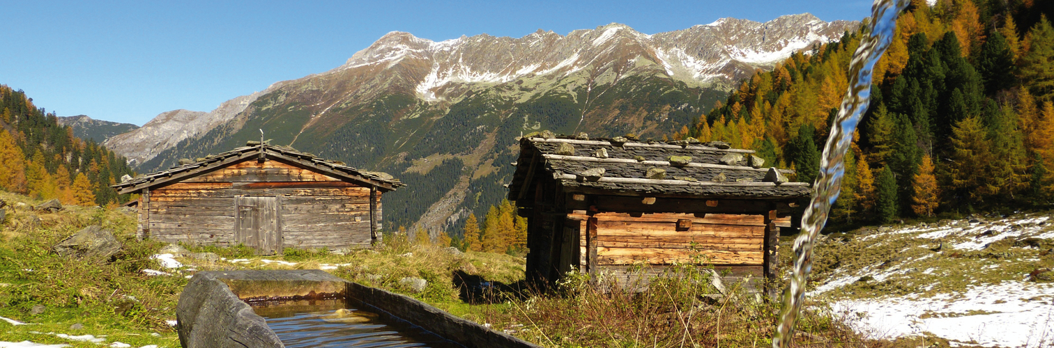 Almhütten mit Holzbrunnen im Herbst