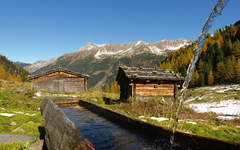 Almhütten mit Holzbrunnen im Herbst