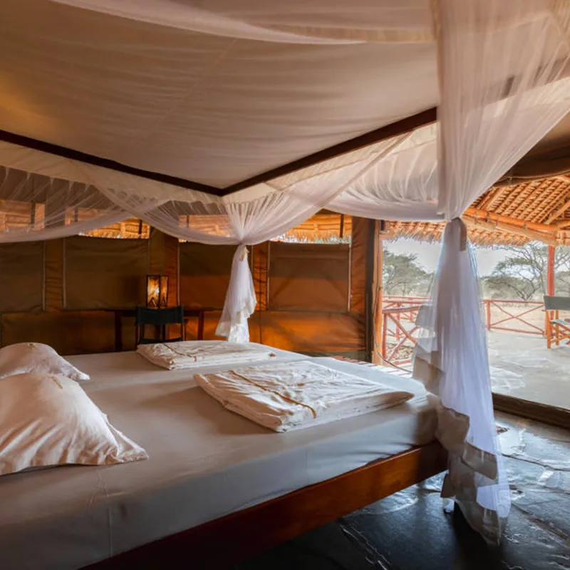 Luxuriöses Schlafzimmer in einer Safari-Lodge mit Blick auf die afrikanische Savanne.