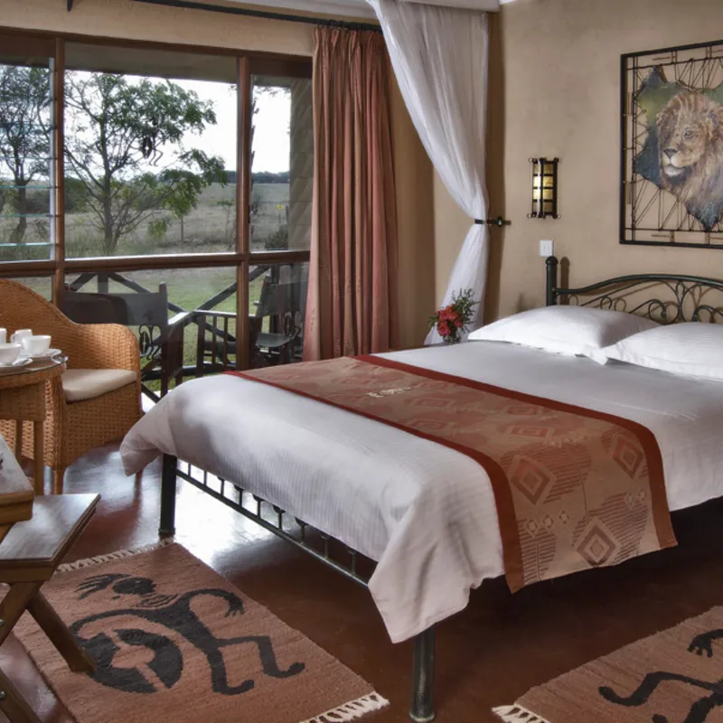 Hotelzimmer in Kenia mit Doppelbett und afrikanischen Dekoelementen.