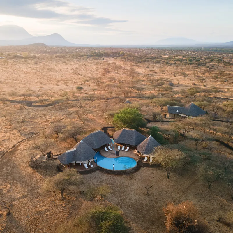 Luftaufnahme einer Safari-Lodge mit Pool in Kenias Savanne.