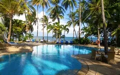 Pool mit Palmen und Meerblick in einem tropischen Resort.