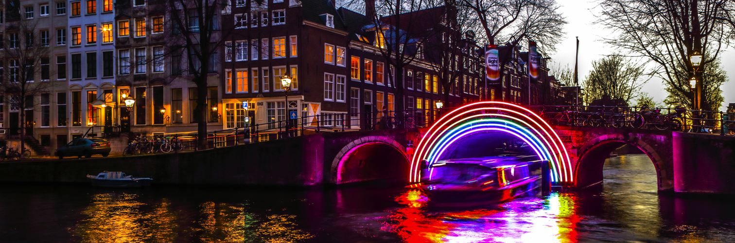 AMSTERDAM, NETHERLANDS - JANUARY 10, 2017: Cruise boats rush in night canals. Light installations on night canals of Amsterdam within Light Festival. January 10, 2017 in Amsterdam - Netherland.
