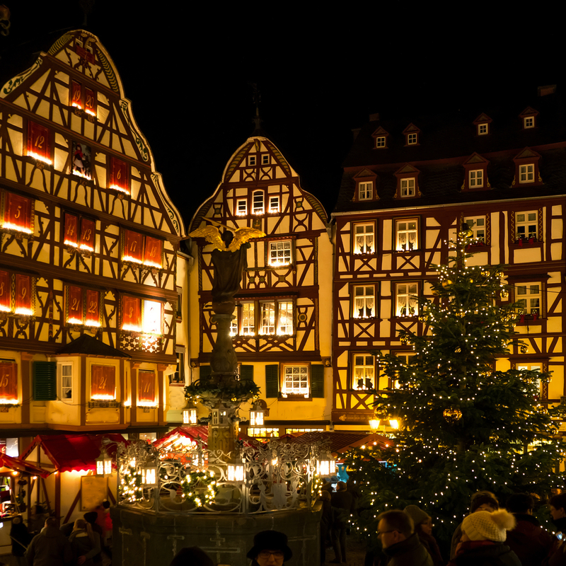 Weihnachtsmarkt bei Nacht mit Fachwerkhäusern und Weihnachtsbaum.