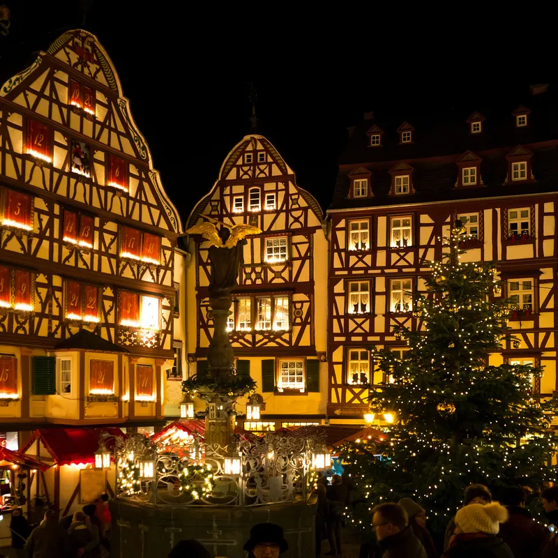 Weihnachtsmarkt bei Nacht mit Fachwerkhäusern und Weihnachtsbaum.