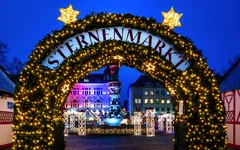 Weihnachtsmarkt-Eingang bei Nacht mit Lichterdekoration.