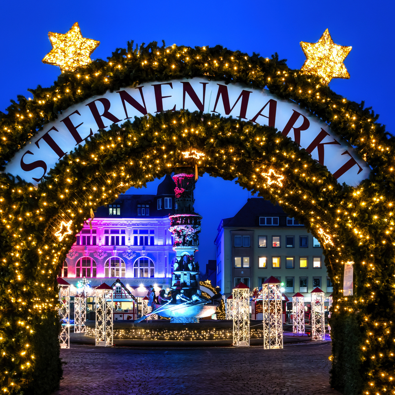 Weihnachtsmarkt-Eingang bei Nacht mit Lichterdekoration.