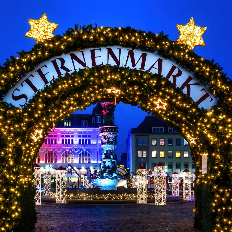 Weihnachtsmarkt-Eingang bei Nacht mit Lichterdekoration.