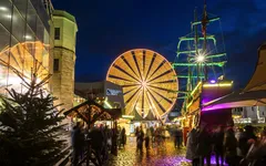 Weihnachtsmarkt am Schokoladenmuseum mit beleuchtetem Riesenrad und Weihnachtsschmuck.