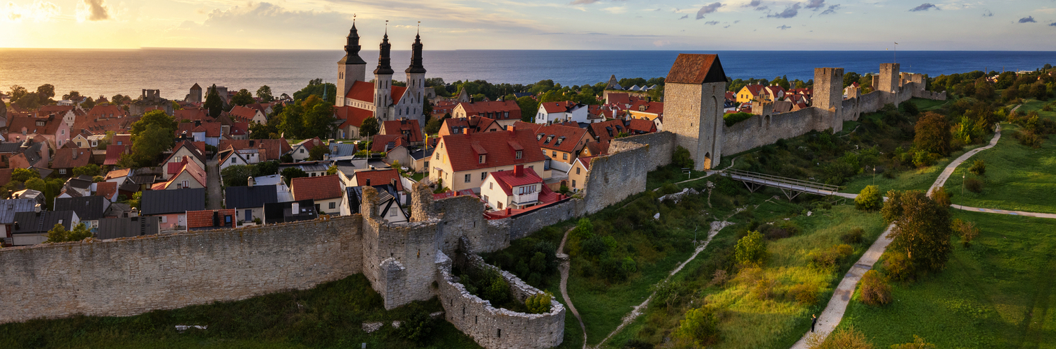 Drohnen-Panoramaaufnahme der Stadt Visby mit der mittelalterlichen Stadtmauer und der Kathedrale bei Sonnenuntergang