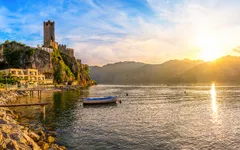 Burg am Ufer eines Sees bei Sonnenuntergang.