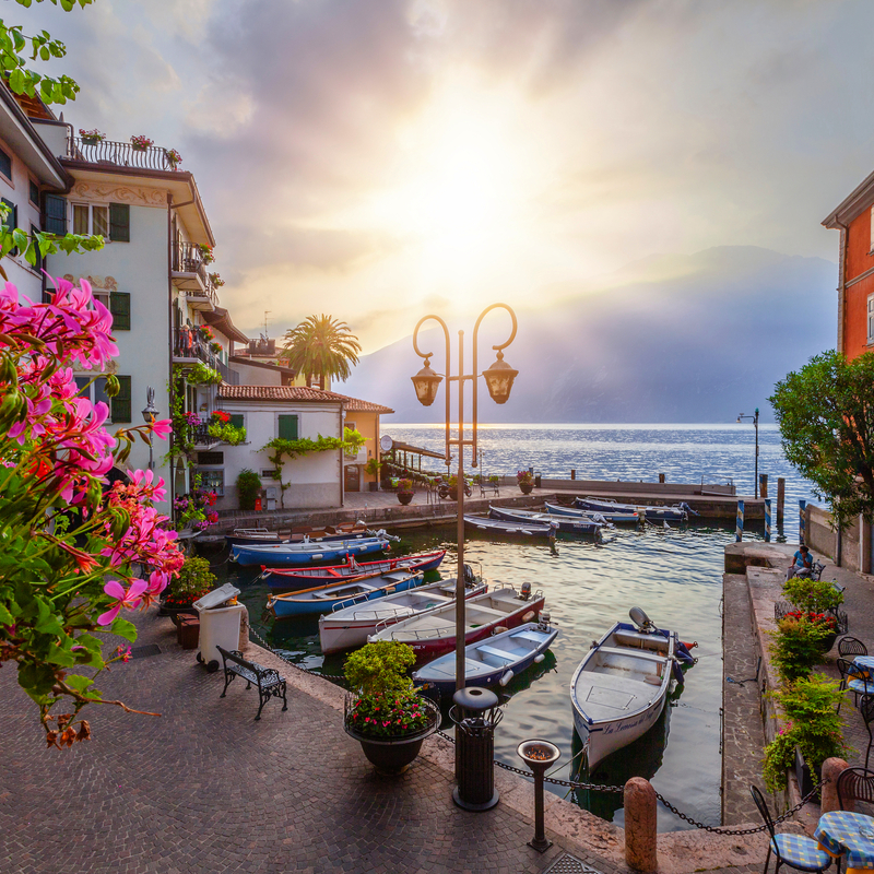 Sonnenaufgang im Hafen von Limone am Gardasee, Boote und mediterrane Umgebung.