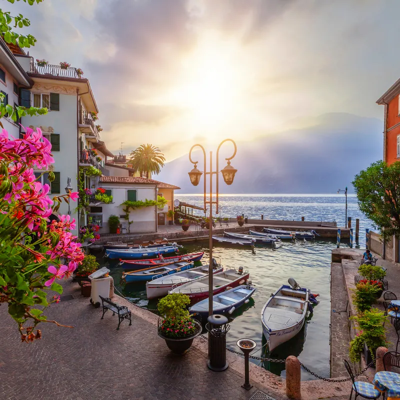 Sonnenaufgang im Hafen von Limone am Gardasee, Boote und mediterrane Umgebung.