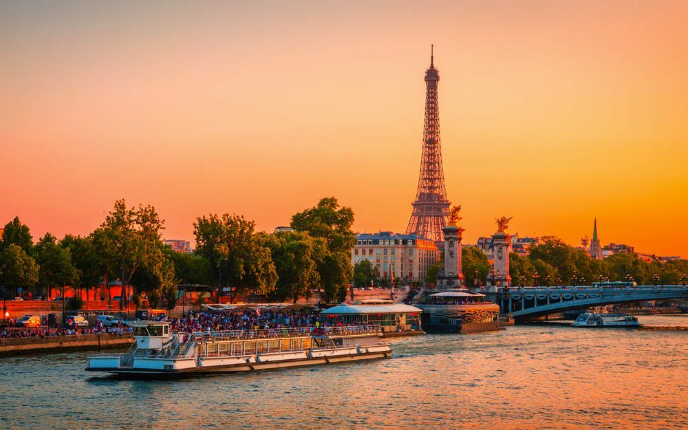 Blick auf den Eiffelturm, die Alexander-III.-Brücke und die Seine bei Sonnenuntergang in Paris, Frankreich