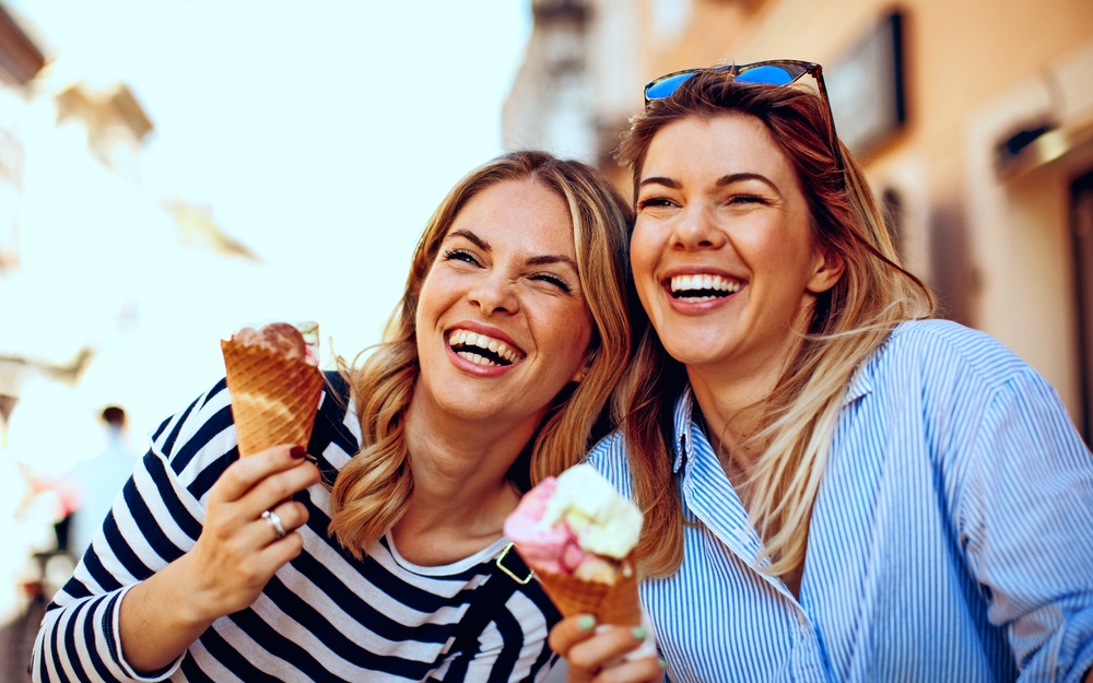 Zwei junge Frauen lachen und halten Eis in der Hand