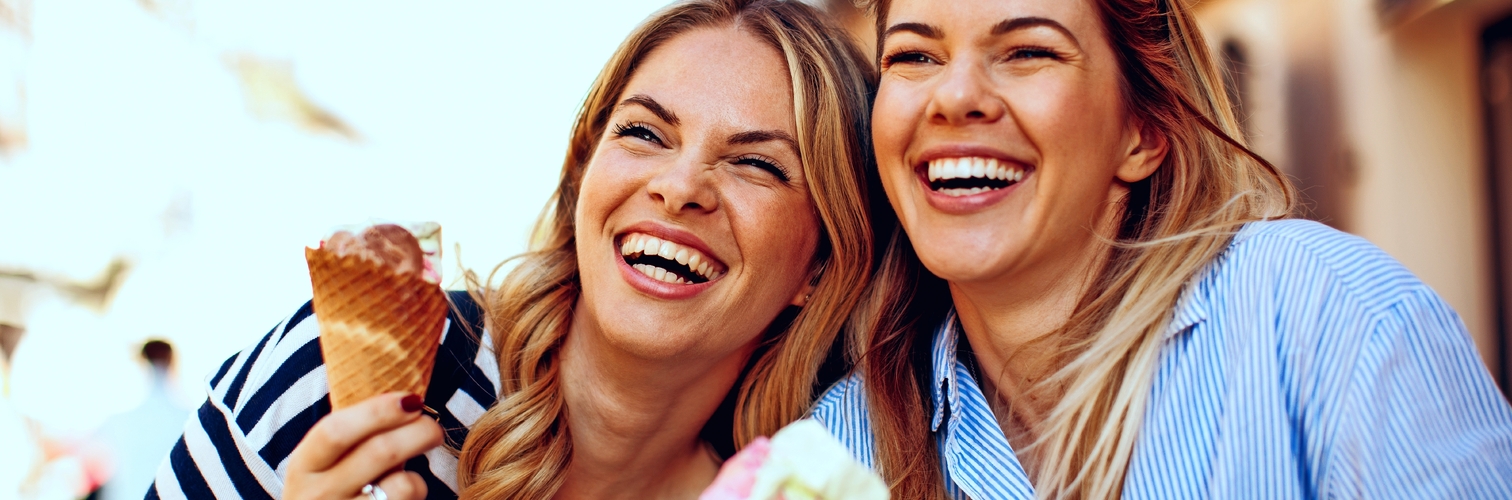 Zwei junge Frauen lachen und halten Eis in der Hand