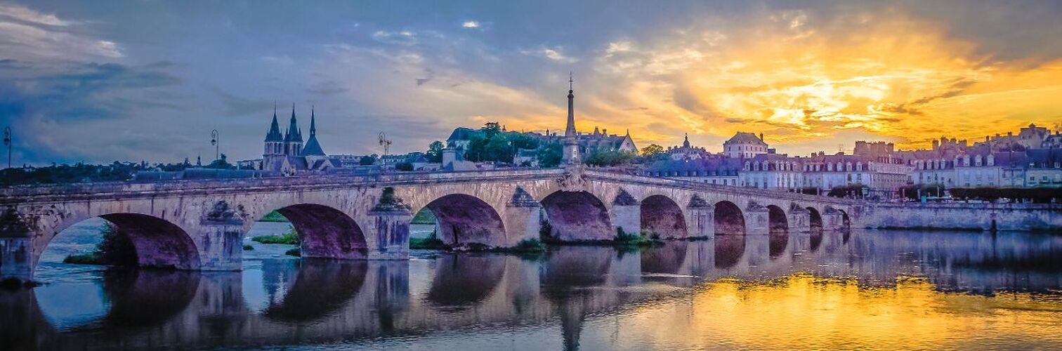Steinbrücke über einen Fluss bei Sonnenuntergang mit reflektierendem Wasser
